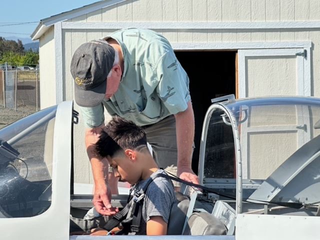 A Young Eagles kid gives a thumbs-up beside a chapter aircraft before a first flight